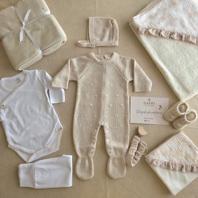Conjunto de roupa de bebé e mantas em tons bege e branco com cartão DAFRI BABY CLOTHING