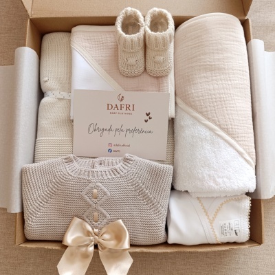 Conjunto de roupa de bebé em caixa de cartão, em cores bege e branco.