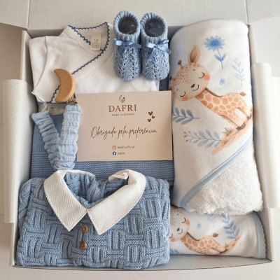 Conjunto de roupa de bebé azul e branca com acessórios e manta com padrão de girafa