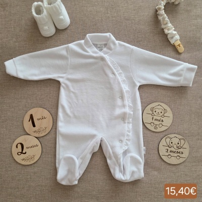 Macacão branco de bebé, sapatinhos brancos e placas de madeira com texto 1 mês e 2 meses num fundo bege