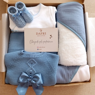 Conjunto de roupa de bebé azul e branco numa caixa de presente