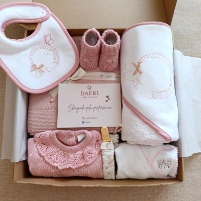 Conjunto de roupa para bebé em caixa de cartão com babete, sapatinhos, camisola e toalha rosa e branco