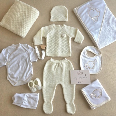 Conjunto de roupa e acessórios de bebé creme e branco com bordados e textura de malha