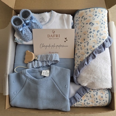 Conjunto de roupa de bebé em caixa com sapatinhos e manta com padrão de coelhos azuis e bejes