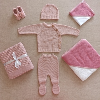 Conjunto de roupa de bebé em malha rosa com mantas e toalhas.