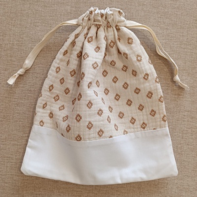 Saco de tecido branco com padrão floral castanho e cordão para fecho