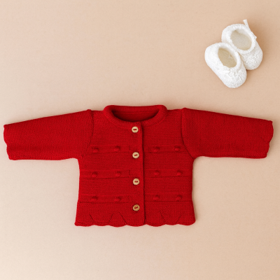 Casaco vermelho de malha para bebé com botões de madeira e sapatinhos brancos felpudos