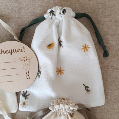 Saco branco com flores bordadas e etiqueta de madeira com texto 'Cheguei!'