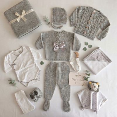 Conjunto de roupa e acessórios de bebé em tons cinza e branco com manta, toalha, gorro, cardigan e babete com figura de leão.