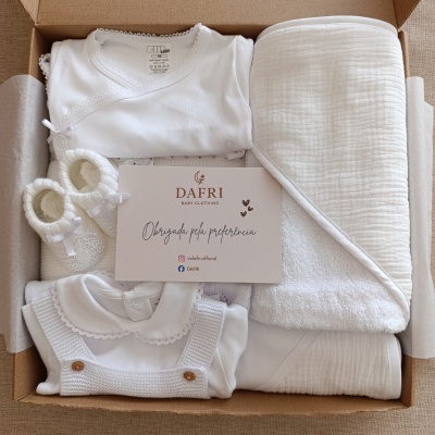 Conjunto de roupa branca de bebé com manta e sapatos em caixa de cartão