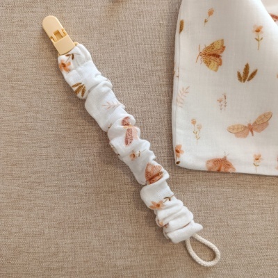 Presilha para chupeta com tecido estampado e clip amarelo claro, com pano estampado ao lado.