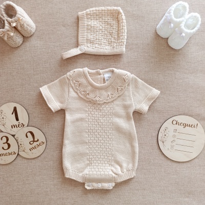 Conjunto de roupa e acessórios de bebé em tons bege com placas de madeira para marcar meses