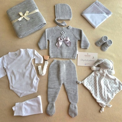 Conjunto de roupa de bebé em lã cinzenta e acessórios sobre fundo bege