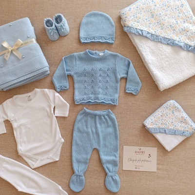 conjunto de roupa azul de bebé com acessórios sobre fundo castanho