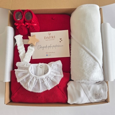 Conjunto de roupa de bebé em caixa de cartão com casaco vermelho de malha, gola branca em tecido, meias vermelhas e toalha branca enrolada