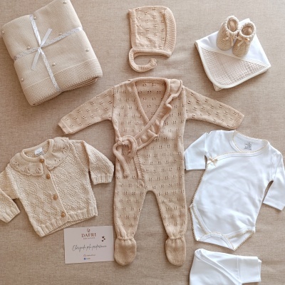 Roupa de bebé bege e branca com cartões e manta
