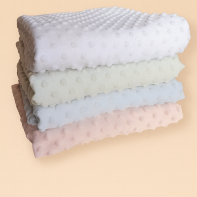 Quatro mantas com textura de bolinhas em relevo em tons pastel sobre fundo bege