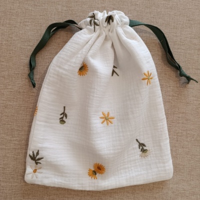 Saco de pano branco com flores bordadas e cordão verde