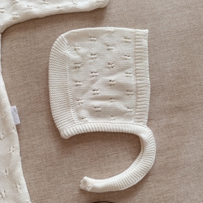 Gorro branco de malha para bebé com padrão de pontos abertos.