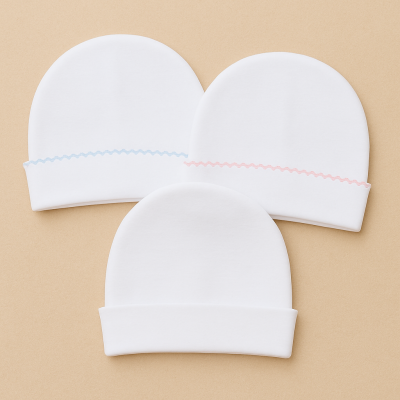 Três gorros de bebé brancos com detalhes de linha azul e rosa
