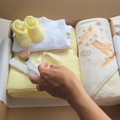 Conjunto de roupa para bebé amarelo e branco com manta estampada de girafa numa caixa com cartão da marca Dafri