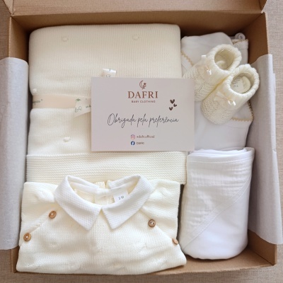 Conjunto de roupa de bebé em tecido tricotado bege claro com botões de madeira e sapatos de malha.