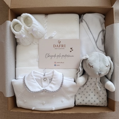 Conjunto de roupa e brinquedo de bebé branco numa caixa de presente com cartão DAFFRI BABY CLOTHING