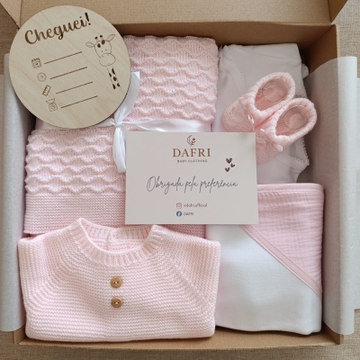 Conjunto de roupa de bebé rosa e branca na caixa com cartão e tábua de madeira decorativa