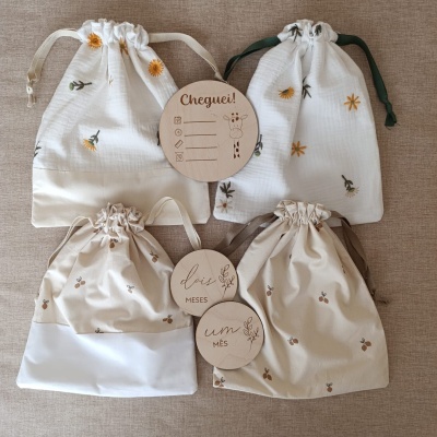 Quatro sacos de algodão com cordão e etiquetas redondas com texto em português