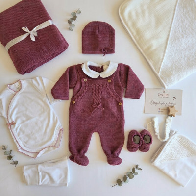 Conjunto de bebé com peças de malha roxa e acessórios brancos dispostos em fundo branco