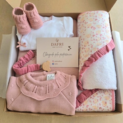 Conjunto de roupa de bebé em tons rosa e branco dentro de caixa de cartão