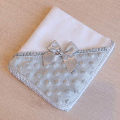 Manta branca e cinza com laço em tecido macio sobre madeira clara