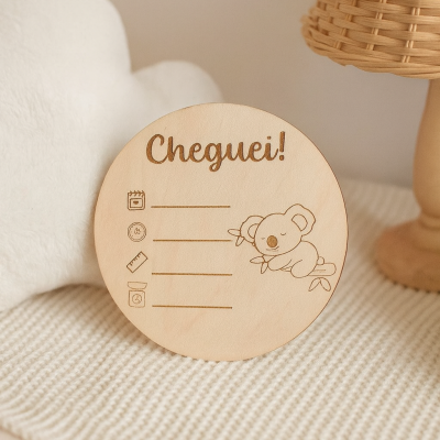 Placa redonda de madeira clara com gravação de coala e texto Cheguei em ambiente acolhedor.