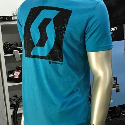 Camiseta azul turquesa com logo preto Scott em manequim dourada