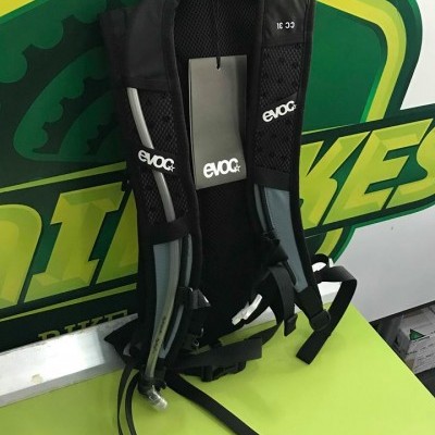 Mochila preta EVOC com alças acolchoadas em fundo verde e amarelo