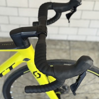 Primeiro plano do guiador preto de bicicleta amarela Scott com travões Shimano