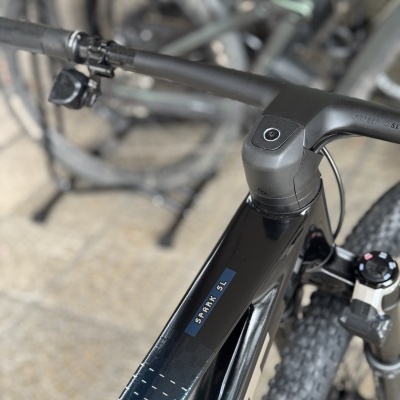 Bicicleta de montanha preta e azul escuro com texto SPARK SL, guiador preto e suspensão dianteira