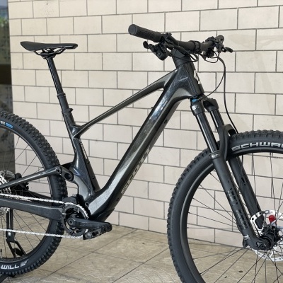 Bicicleta elétrica de montanha preta junto a parede branca de tijolos