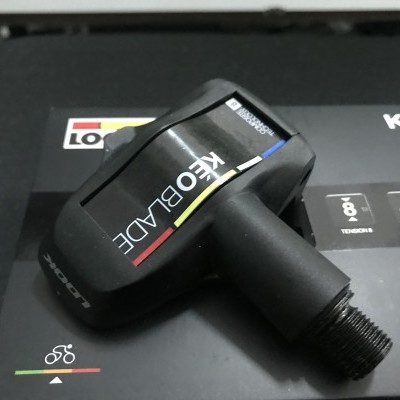 Pedal de bicicleta KÉO BLADE preto sobre embalagem preta com detalhes coloridos.