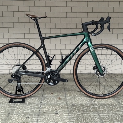 Bicicleta de estrada com quadro preto e verde metálico e pneus castanho-bege