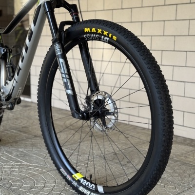 Roda dianteira de bicicleta de montanha com pneu preto MAXXIS REKON RACE e garfo ROCK SHOX