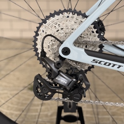 Roda traseira de bicicleta com cassete prateado, desviador SHIMANO GRX e quadro azul claro SCOTT