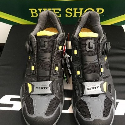 Sapatilhas desportivas pretas e cinza com detalhes amarelos e fecho por fio.