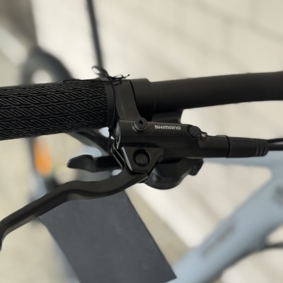 Manípulo preto de bicicleta com manete de travão Shimano perto de parede de tijolo branca