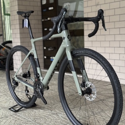 Bicicleta de estrada/cross cinzenta e preta com travões de disco, pneus grossos e caixa de roda moderna