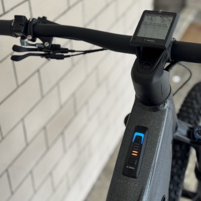 Guiador elétrico de bicicleta preta com ecrã BOSCH e mostrador de bateria em estrutura cinzenta fosca junto a parede
