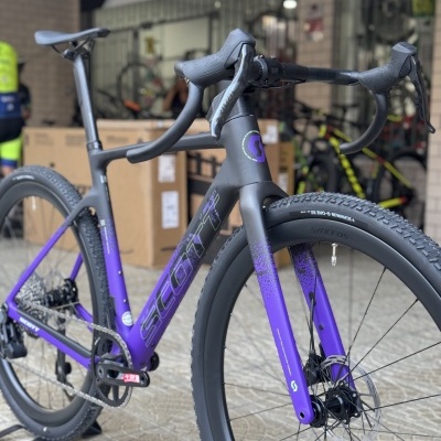 Bicicleta Scott de corrida preto e roxo com rodas Syncros e pneus Schwalbe num interior