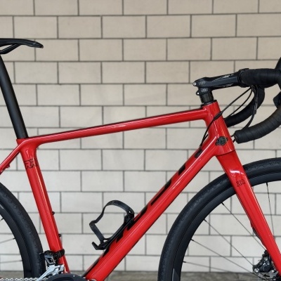 Bicicleta de estrada vermelha com quadro em alumínio junto a uma parede de blocos de cimento