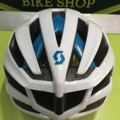 Capacete de bicicleta branco e azul com detalhes pretos e o texto BIKE SHOP ao fundo