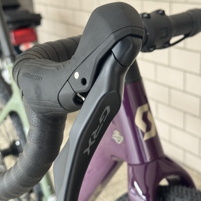 Punho da bicicleta com manete de travão GRX e fita preta, estrutura roxa com logótipo SC